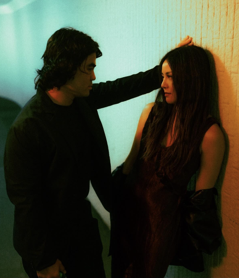 A couple beside a coloured wall
